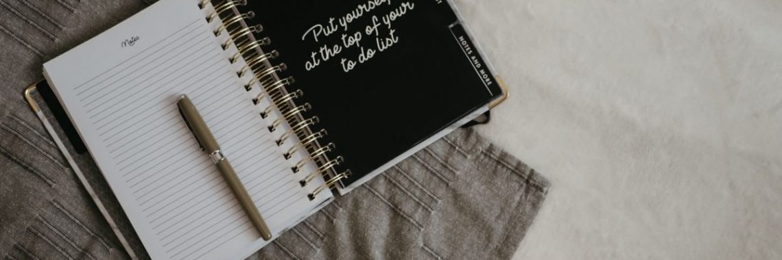 Stylish flatlay featuring a planner with quote, pen, and eyeglasses on a neutral background.
